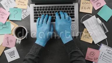 他在家里<strong>戴</strong>着<strong>医用手套</strong>的笔记本电脑工作，他注意到工作场所到处都是。